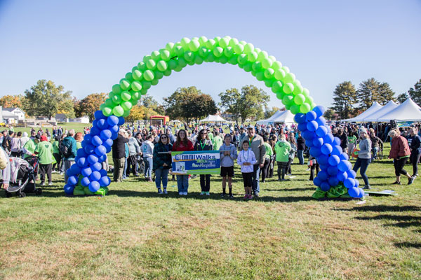People standing under a balloon arch holding a banner for NAMIWalks New Hampshire