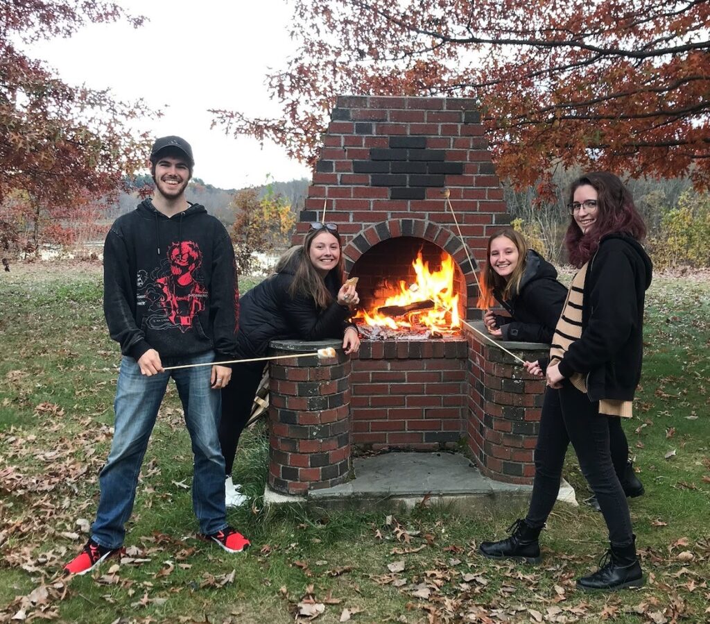 Four individuals standing in front of an outdoor fireplace